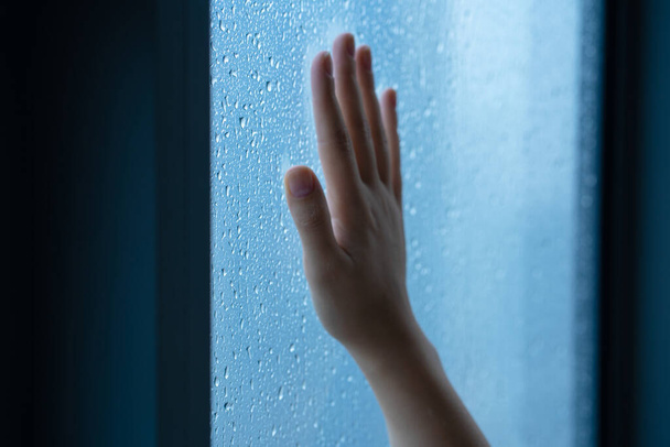 Female hand at the window during the rain. Glass in drops of water - Valokuva, kuva