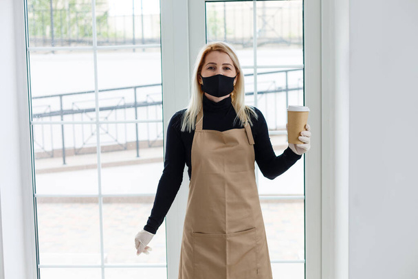 vrouwen met een beschermend masker staande in cafe tijdens covid-19 voorkomen. - Foto, afbeelding