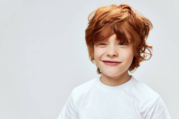 Sly red-haired boy with narrowed eyes conceived something bad white t-shirt cropped view  - Foto, Imagem