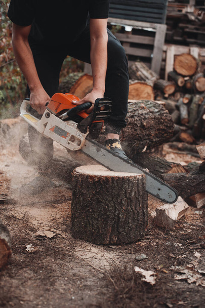 Young man works with a chainsaw on backyard - Photo, Image
