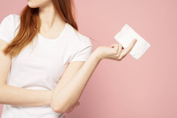 Červenovlasá žena s bločkem v ruce a v bílém tričku na růžovém pozadí hygienické péče o vzhled - Fotografie, Obrázek