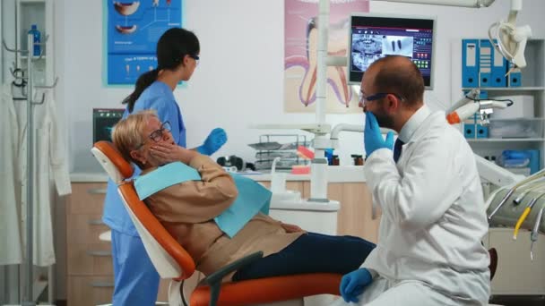 Vecchio paziente toccando guancia mostrando dente con dolore - Filmati, video