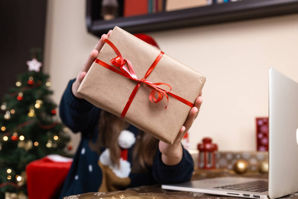 Um presente de Natal. Mulher retrato sem rosto segurando caixa de presente com fita vermelha em um fundo de Natal. Ano Novo feriados conceito - Foto, Imagem