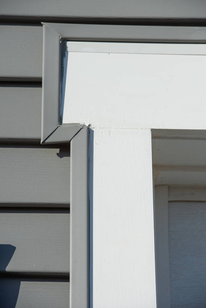 新しいアメリカの家の暗い緑の灰色の水平ビニールサイドで白い窓枠を閉じるビュー - 写真・画像