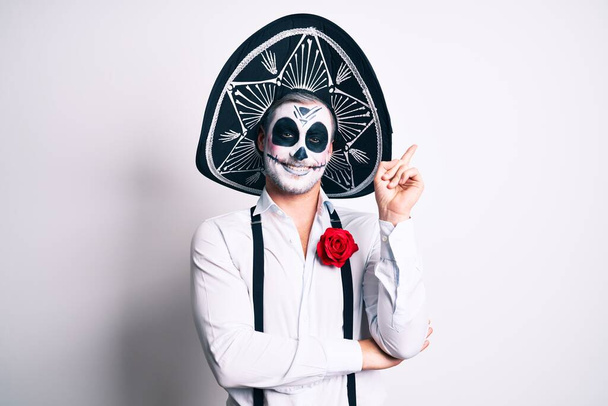 Homme portant le jour du costume mort sur blanc souriant heureux pointant avec la main et le doigt sur le côté  - Photo, image