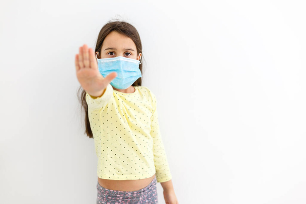 Egy kislány egy eldobható maszkban, könnyű háttérrel. koronavírus járványvédelem - Fotó, kép