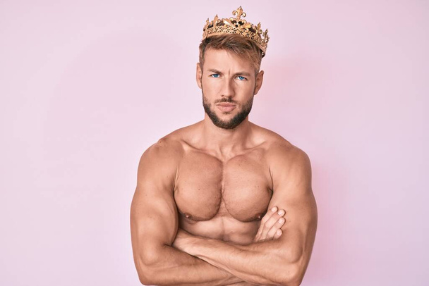 Young caucasian man shirtless wearing king crown skeptic and nervous, disapproving expression on face with crossed arms. negative person.  - Zdjęcie, obraz