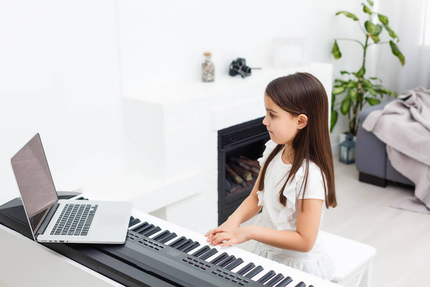 Meisje dat piano leert spelen tijdens quarantaine. Coronavirusconcept. - Foto, afbeelding