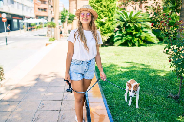 Giovane bella donna bionda che porta fuori il cane in una giornata estiva - Foto, immagini