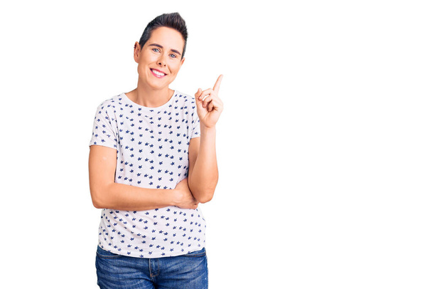 Young woman with short hair wearing casual clothes smiling happy pointing with hand and finger to the side  - Photo, Image
