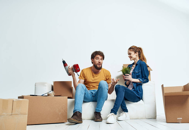 Man and woman sit on white couch boxes with moving lifestyle things - Foto, imagen