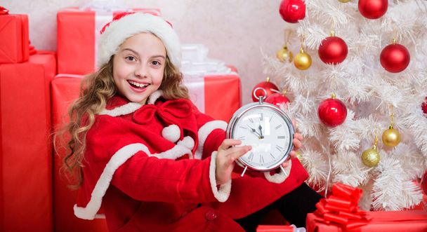 Merry christmas concept. Last minute till midnight. Waiting for miracle. New year countdown. Girl kid santa hat hold clock excited happy face counting time to new year. Last minute new years eve plan - Valokuva, kuva