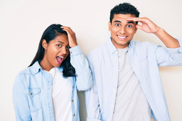 Beautiful latin young couple wearing casual clothes surprised with hand on head for mistake, remember error. forgot, bad memory concept.  - Fotoğraf, Görsel