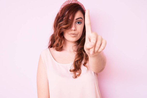 jonge mooie vrouw dragen casual kleding wijzen met vinger omhoog en boze uitdrukking, tonen geen gebaar  - Foto, afbeelding