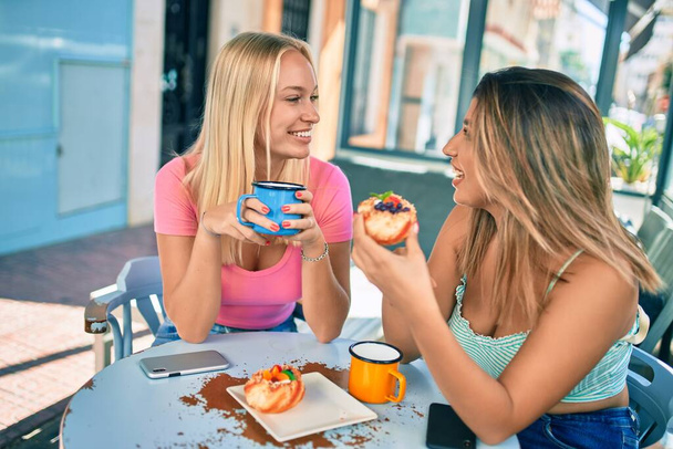 Duas amigas bonitas e jovens juntos se divertindo na cafetaria - Foto, Imagem