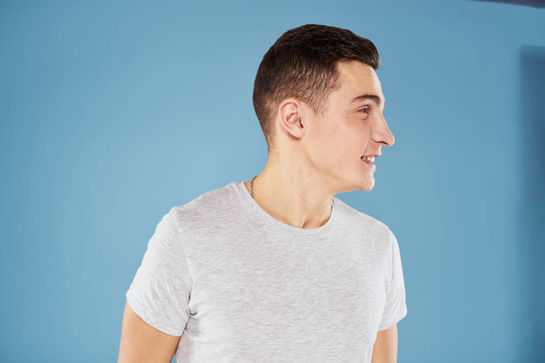 Emotionele man in wit t-shirt bijgesneden uitzicht op blauwe achtergrond levensstijl - Foto, afbeelding