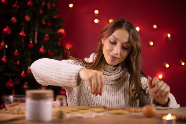 Joululeipomo. kaunis hymyilevä tyttö koristelu juuri leivottu joulun evästeet - Valokuva, kuva