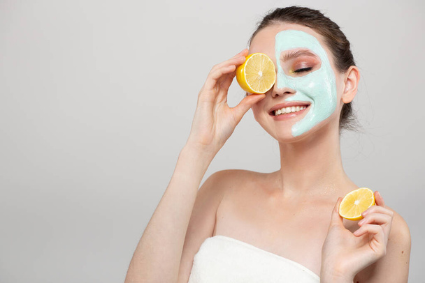 Beautiful young smile woman holding fresh lemon and orange slices. Skin care, spa, natural beauty and cosmetology concept, on gray background copyspace - Photo, Image