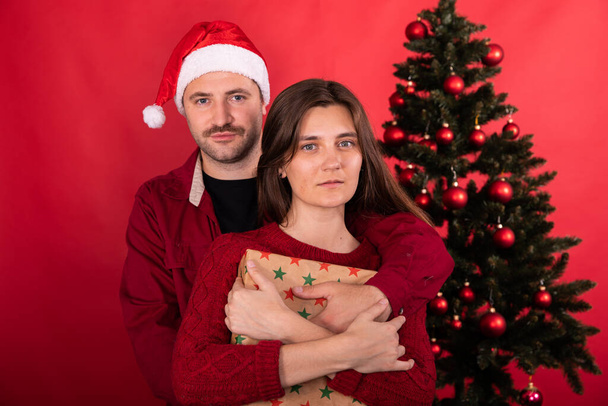 Bella giovane coppia in posa a casa davanti all'albero di Natale, vacanze invernali in famiglia - Foto, immagini