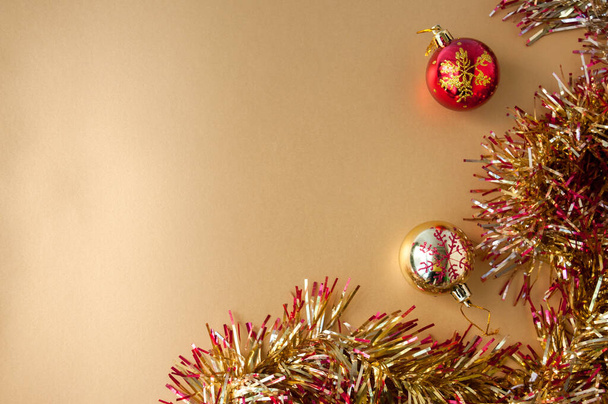 New year's still life: two Christmas balls and tinsel on a gold background, space for text - Fotoğraf, Görsel