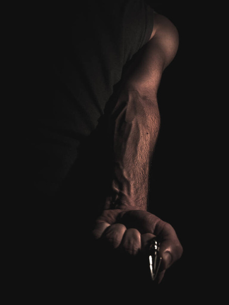 A low angle shot of an arm of a man with visible veins and an arrowhead in his hand - Photo, image