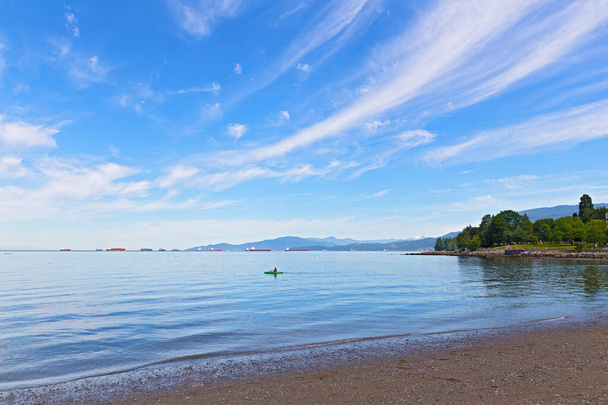 Panoramic view of English Bay with horizon over water and mountains, Vancouver, British Columbia, Canada. Kayak, seagulls, nautical vessels and snow mountain peaks in bay landscape on a sunny day. - Valokuva, kuva
