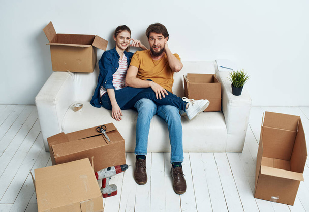 man and woman on the couch moving boxes renovation work leisure interior room - Photo, Image