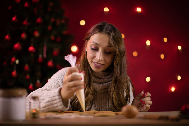 Χριστουγεννιάτικο ψήσιμο. Νεαρή όμορφη γυναίκα κάνει τζίντζερ Χριστούγεννα μπισκότα στο σπίτι - Φωτογραφία, εικόνα