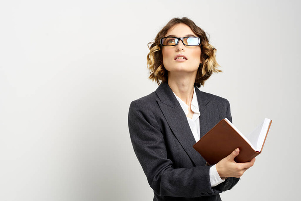 Geschäftsfrau im klassischen Anzug mit Notizbuch in der Hand und Brille im Gesicht. - Foto, Bild
