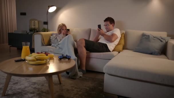 Couple compétitif jouant à des jeux mobiles sur leurs smartphones à la maison  - Séquence, vidéo