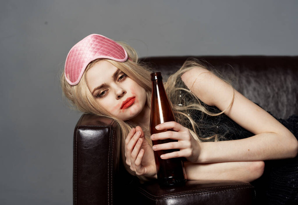 žena s lahví piva na pohovce alkohol závislost spánek maska na hlavě - Fotografie, Obrázek