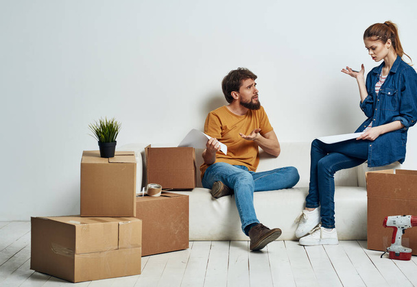 Чоловік і жінка коробки з речами білий диван інтер'єр рухома кімната
 - Фото, зображення