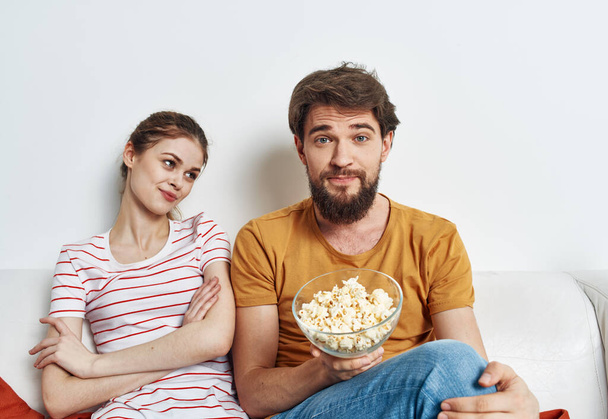Man and woman on the couch with popcorn watching TV shows - Fotó, kép