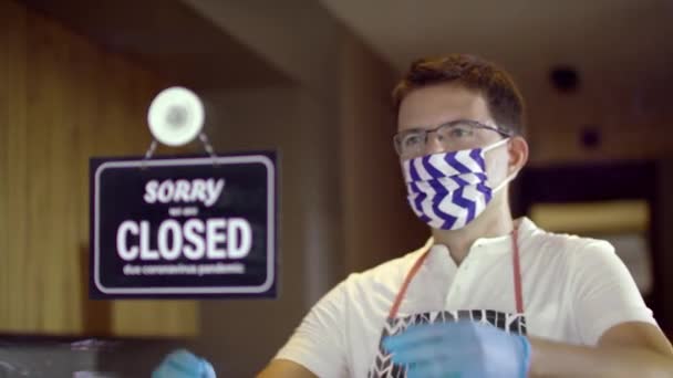Красивий кавказький працівник носить захисну маску для обличчя, закриту для відкриття знаку на вікні через пандемію
 - Кадри, відео