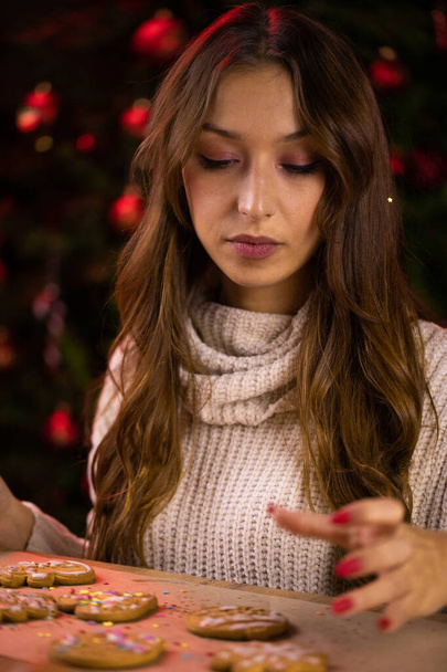Joululeipomo. Ajattelevainen surullinen tyttö koristelu joulun piparkakut evästeet - Valokuva, kuva