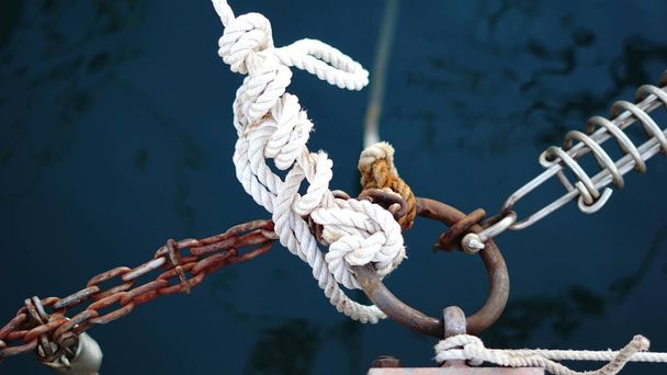 cuerdas y cadenas atadas en arandela metálica en el puerto - Foto, Imagen