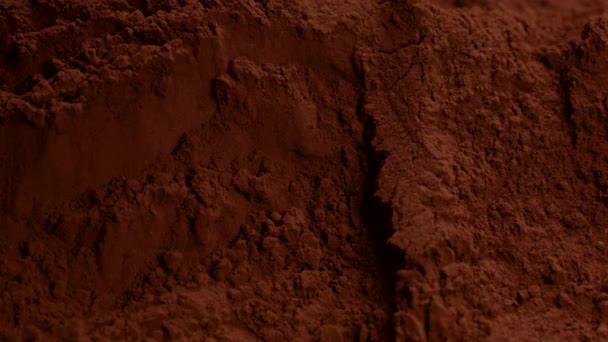 Tmavé kousky čokolády padají v kakaovém prášku a dělají šplouchání, pomalu - Záběry, video