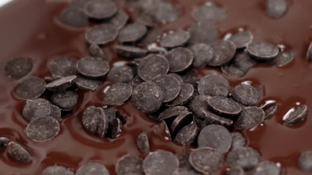 Las chispas de chocolate dulce caen en chocolate fundido oscuro, primer plano, cámara lenta - Metraje, vídeo
