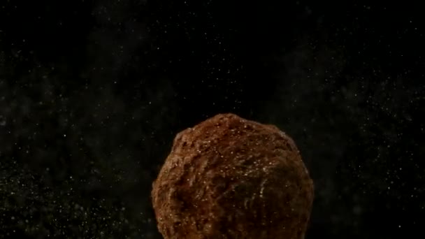 Macro schot chocolade truffel spinnen in gouden glanzende glitter stof, slow mo - Video