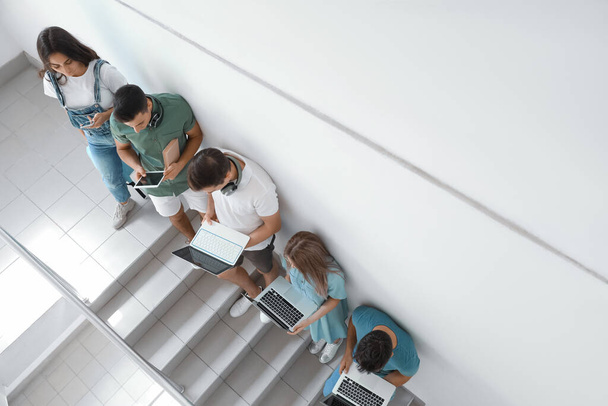 Studenten met moderne apparatuur op trappen aan de universiteit - Foto, afbeelding