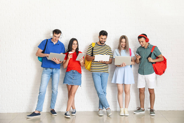 Estudiantes con dispositivos modernos cerca de la pared de luz - Foto, Imagen