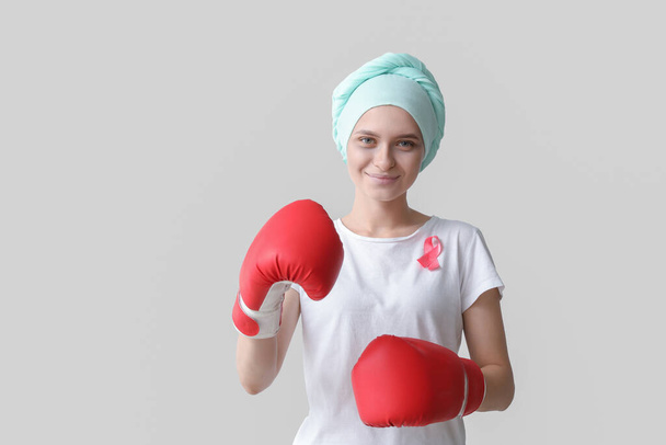Kobieta po chemioterapii w rękawiczkach bokserskich na szarym tle. Świadomość raka piersi - Zdjęcie, obraz