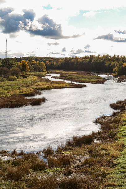 Uitzicht op het platteland van de rivier de Venta stroomt in de buurt van bos in de herfst. Foto genomen in warme herfstdag. - Foto, afbeelding