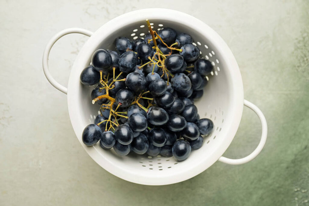 Colador con uvas maduras dulces en la mesa - Foto, imagen