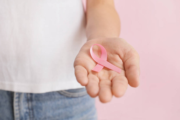 Женщина с розовой лентой на цветном фоне, крупным планом. Концепция информированности о раке груди - Фото, изображение