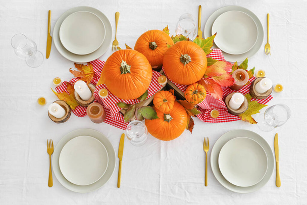 Beautiful table setting with pumpkins and autumn leaves in dining room - Fotó, kép