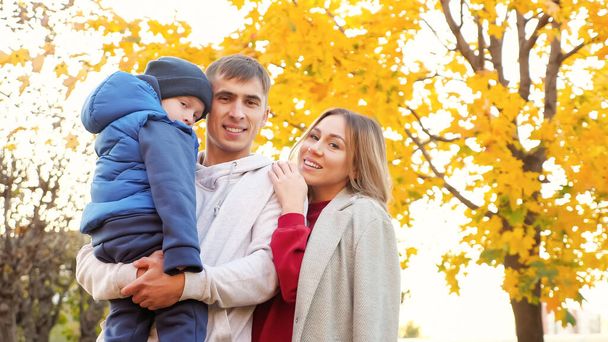 秋の都市公園で面白い男の子の抱擁を持つ素敵な家族 - 写真・画像
