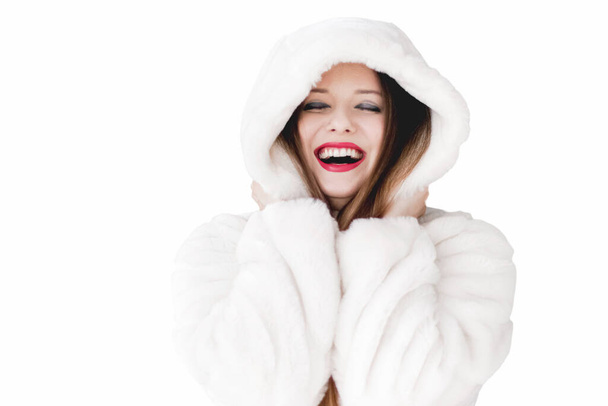 Young woman in fluffy fur coat with hood wrap, warm winter clothing for fashion and Christmas holidays - Photo, image