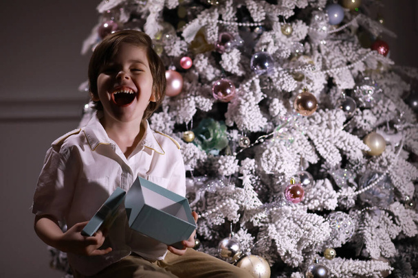 Niño con ropa elegante delante del árbol de Navidad. Esperando el año nuevo. - Foto, Imagen