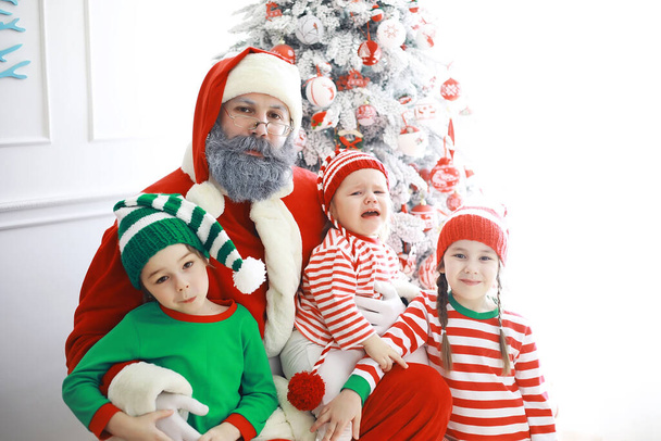 Noel Baba 'nın yardımcıları. Noel' de Noel için dekore edilmiş bir odada elf kostümleri giymiş şirin çocuklar. Mucizeler zamanı. Noel Baba 'dan hediyeler - Fotoğraf, Görsel